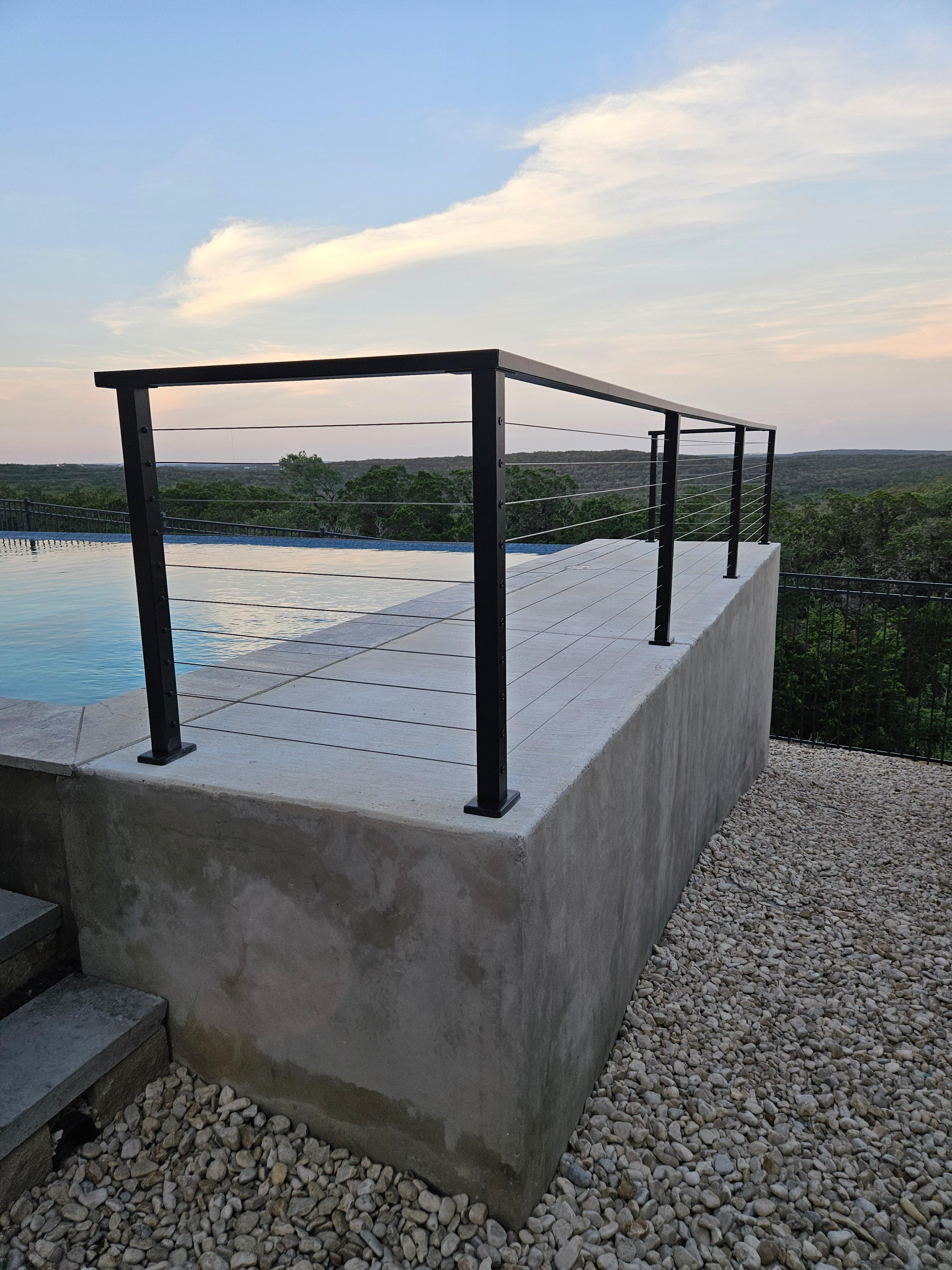 Concrete deck with metal railing overlooking lake by Risen Remodeling in New Braunfels TX